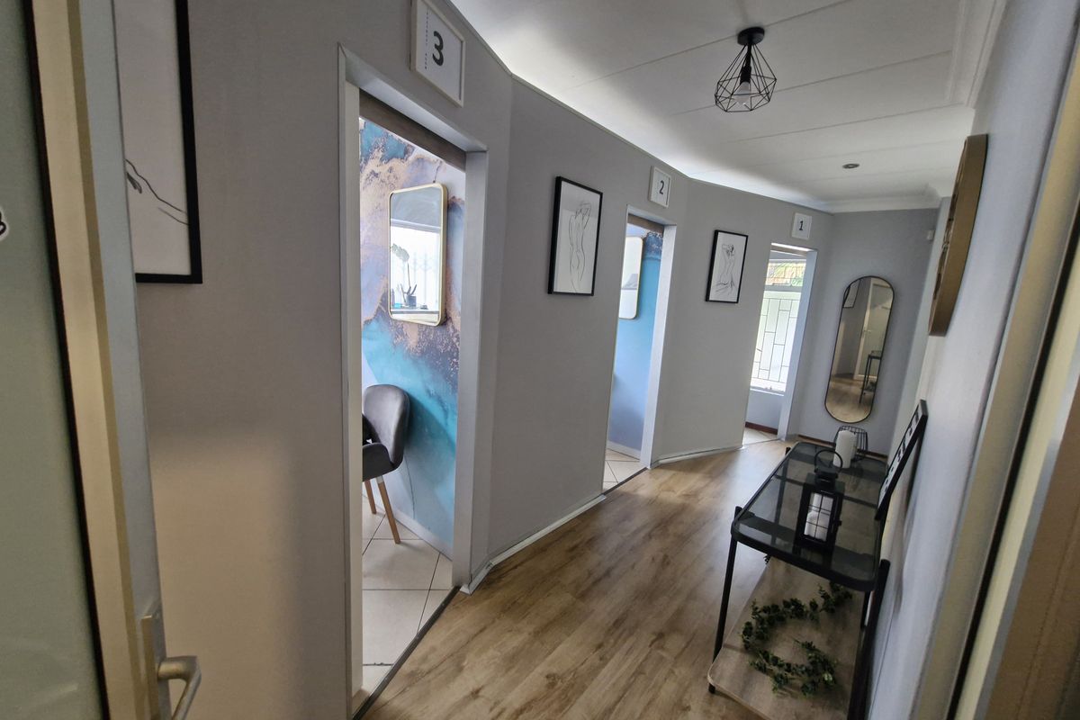 A well-lit commercial hallway featuring laminate flooring and numbered access points to individual rooms, providing a clean and professional circulation space.