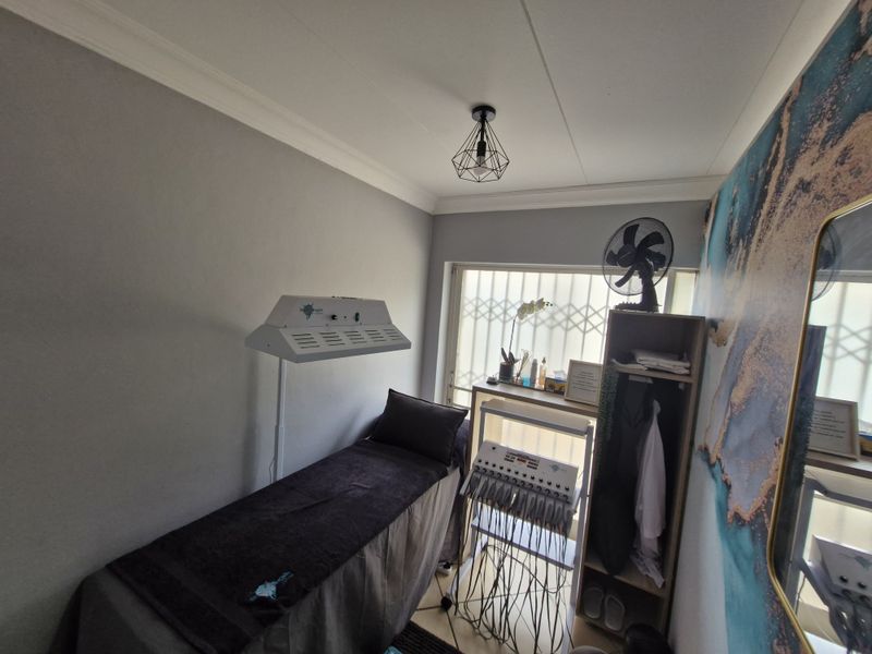 A compact treatment room featuring neutral walls, a decorative accent wall, and a security gate over the window.