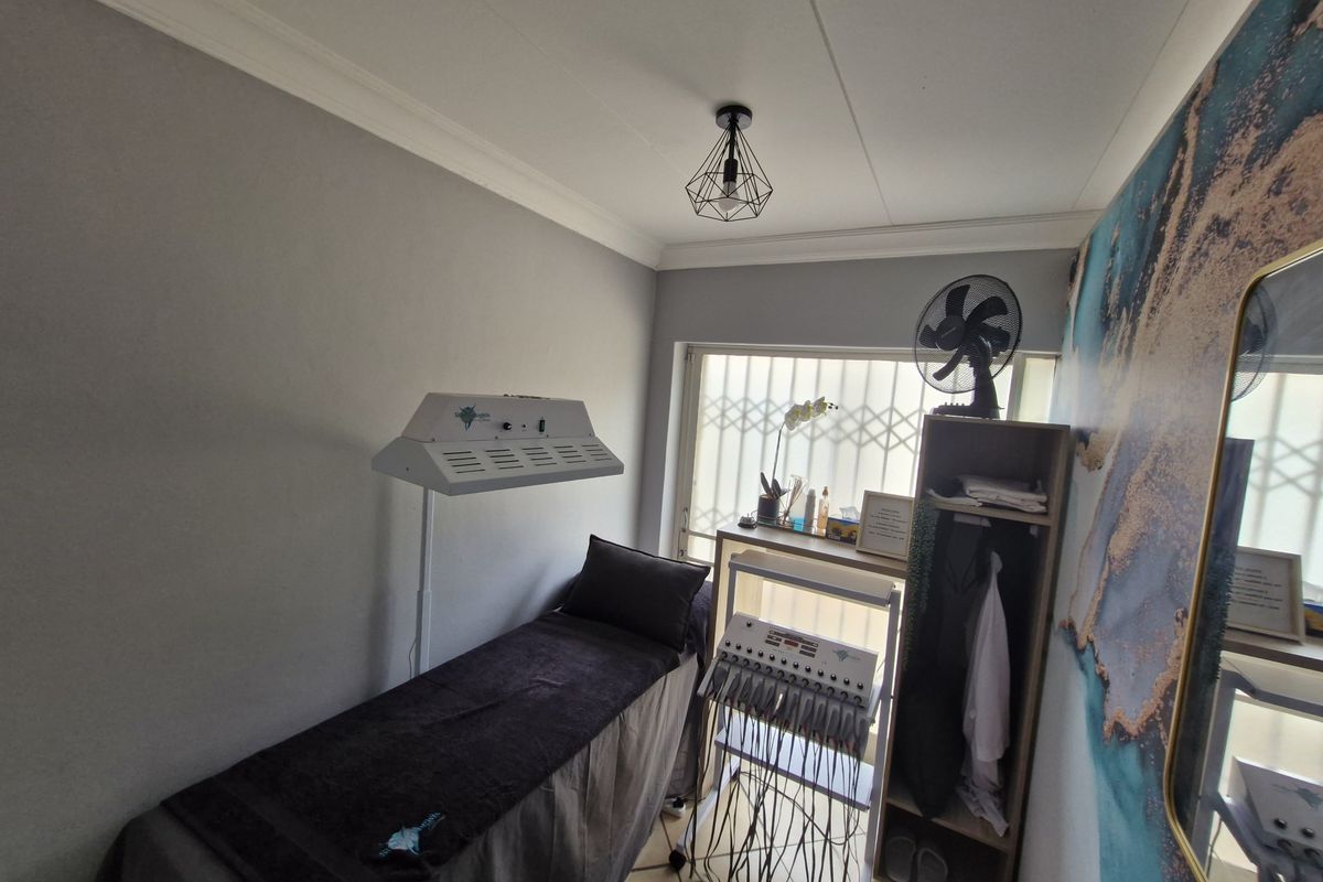 A compact treatment room featuring neutral walls, a decorative accent wall, and a security gate over the window.