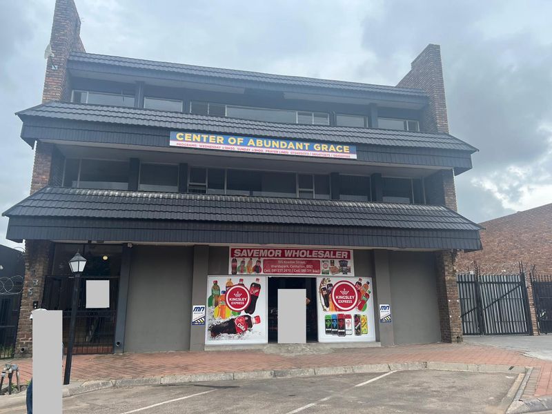 Front elevation of a multi-story commercial building featuring brick construction, tiled roofing, and ground-floor retail signage.