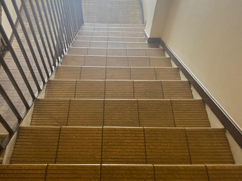 A functional interior staircase featuring tiled steps and a metal balustrade, providing access between levels in this commercial property.