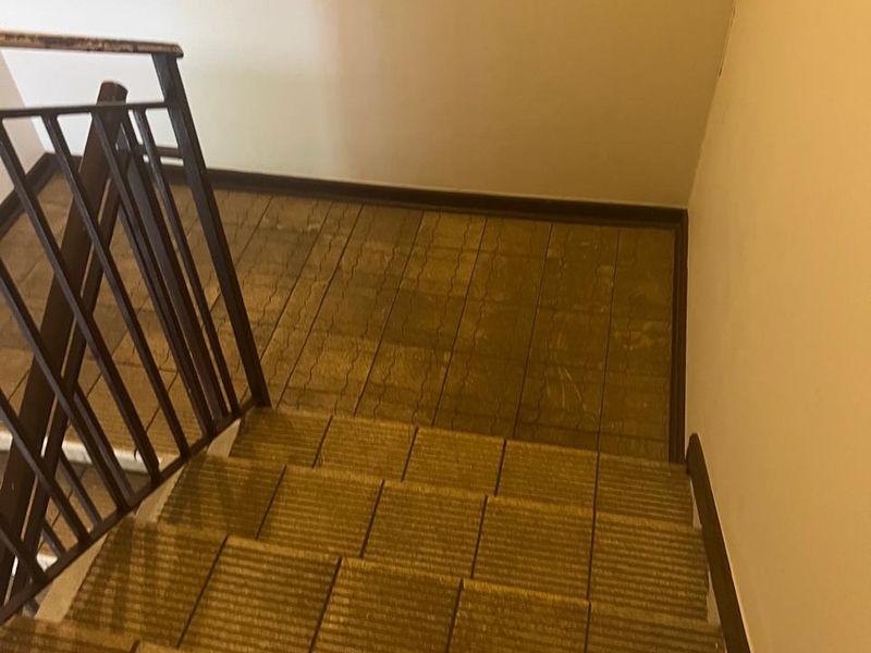 A functional staircase area featuring tiled steps and a metal safety railing, showing signs of wear and requiring cosmetic updates.