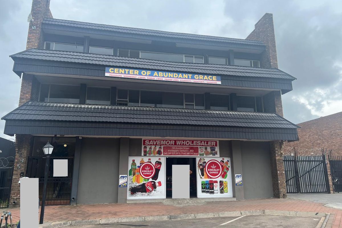 Front elevation of a multi-story commercial building featuring brick construction, tiled roofing, and ground-floor retail signage.