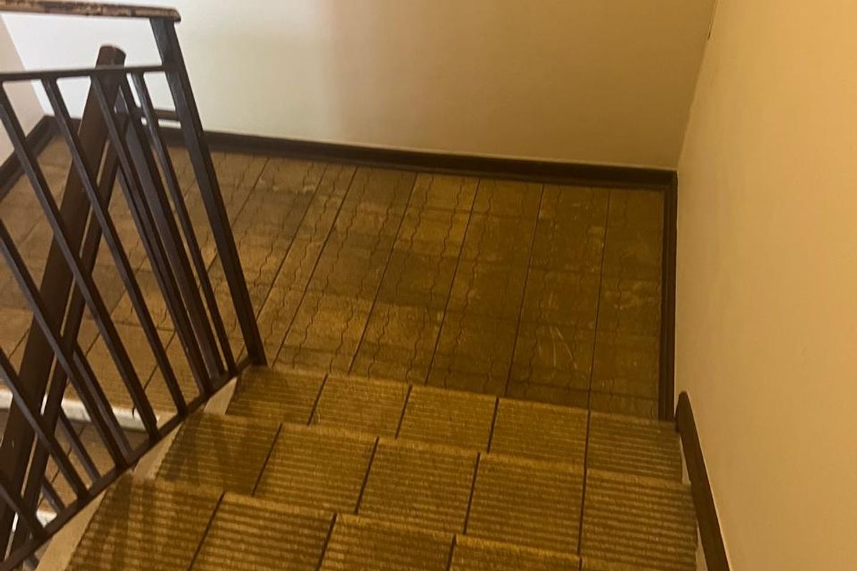 A functional staircase area featuring tiled steps and a metal safety railing, showing signs of wear and requiring cosmetic updates.