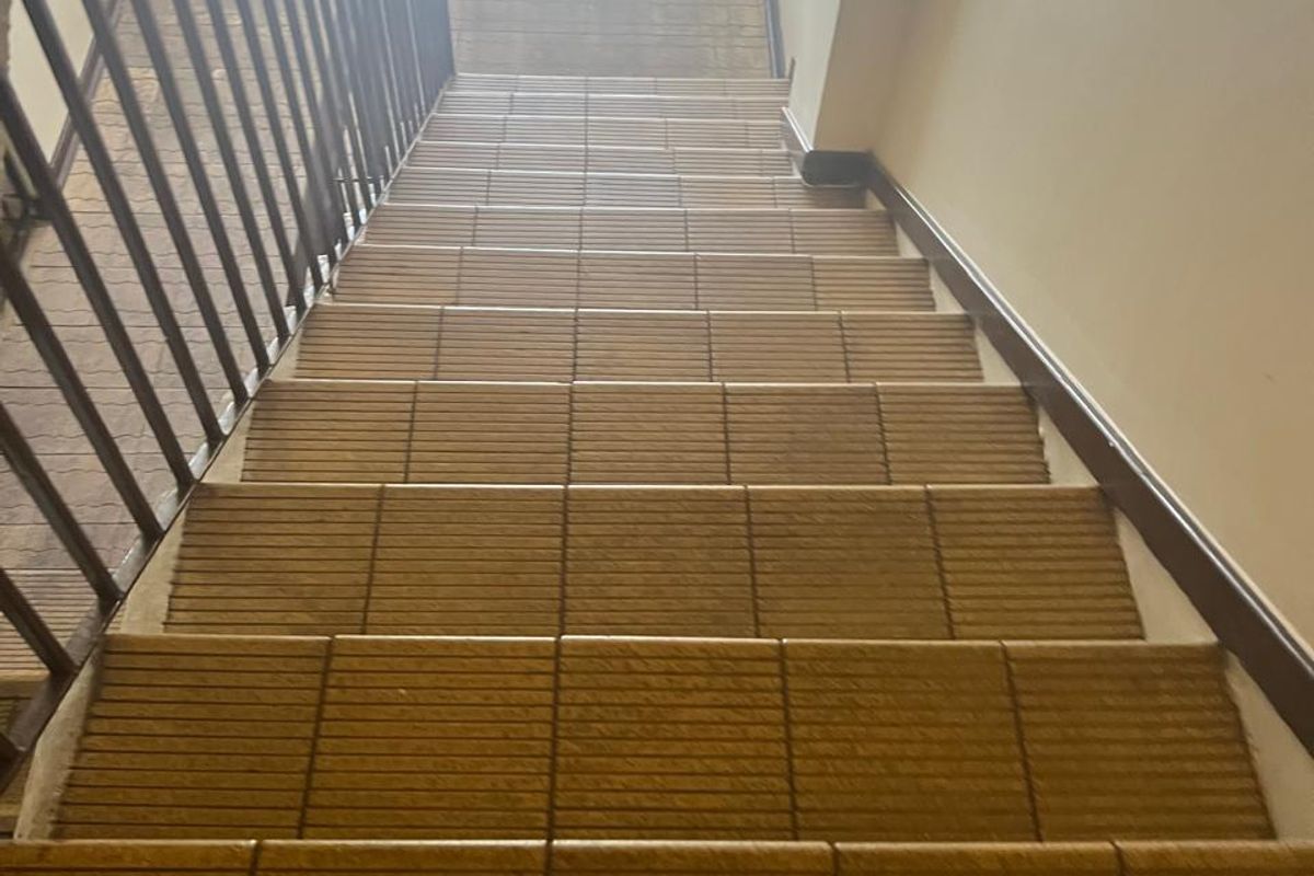 A functional interior staircase featuring tiled steps and a metal balustrade, providing access between levels in this commercial property.