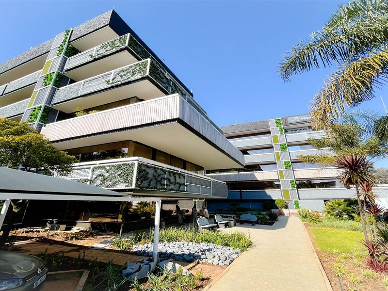 Modern multi-story office building featuring integrated vertical gardens, private balconies, and a well-maintained landscaped exterior with covered parking facilities.