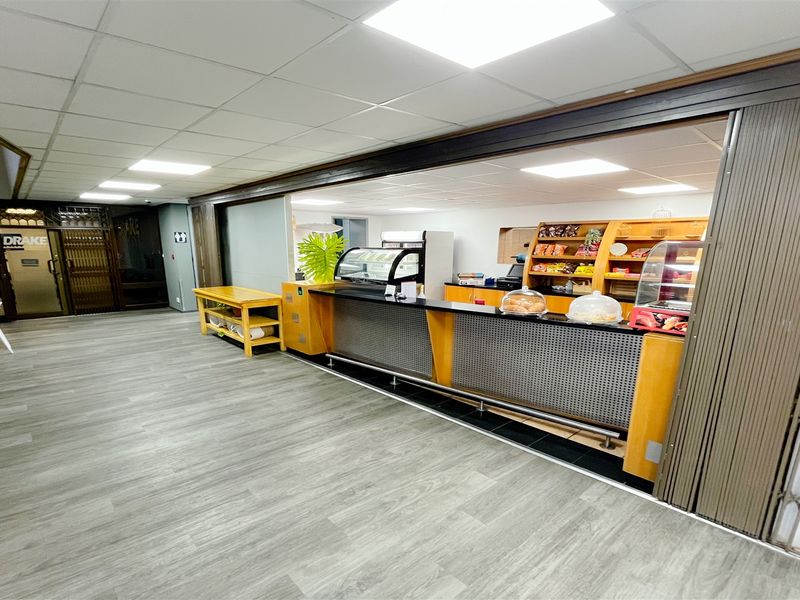 A functional office canteen or service area featuring a built-in service counter, suspended ceiling, and durable laminate flooring.