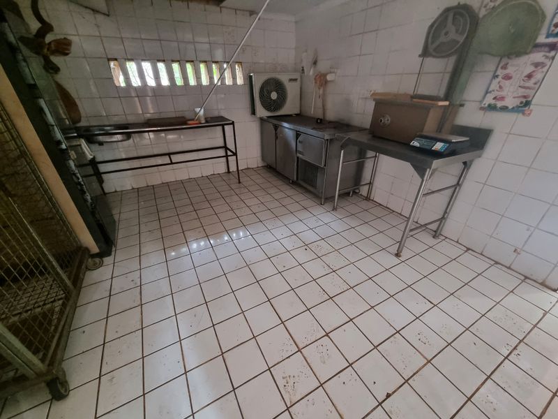 A functional utility or processing space featuring tiled surfaces, stainless steel prep tables, and integrated ventilation, suitable for farm-related operations.