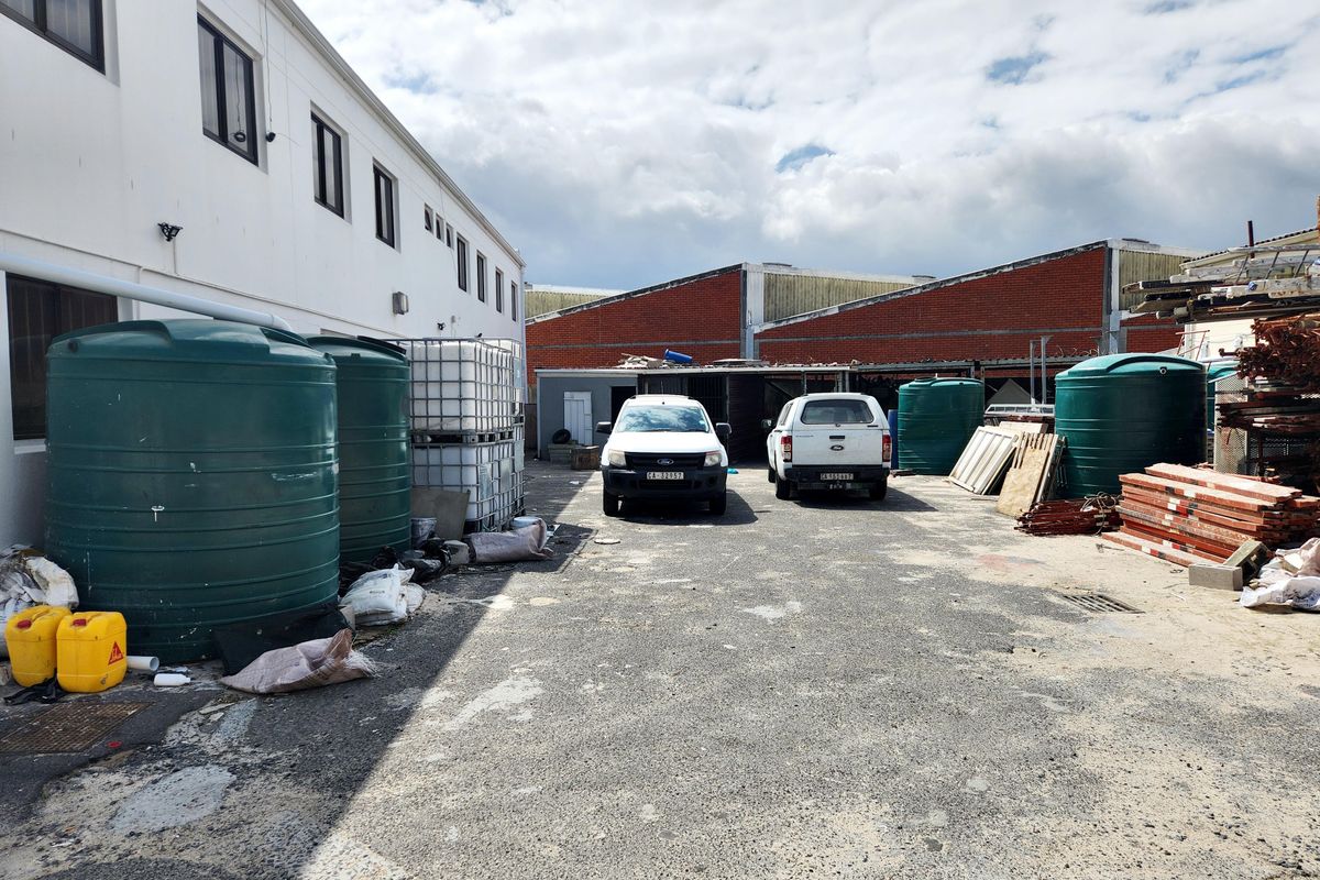 Commercial exterior yard space featuring asphalt paving, large water storage tanks, and access to industrial building structures.