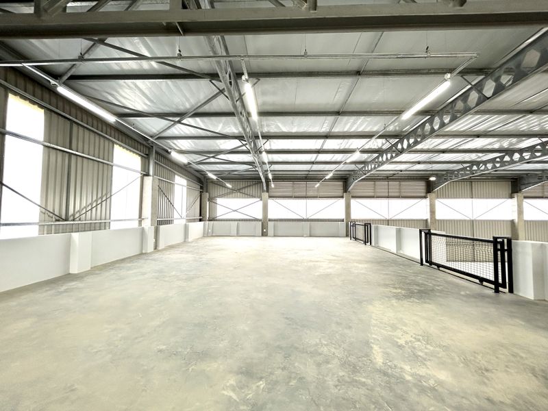 Spacious industrial utility area featuring exposed steel roof trusses, metal wall cladding, and durable concrete flooring with integrated safety railings.