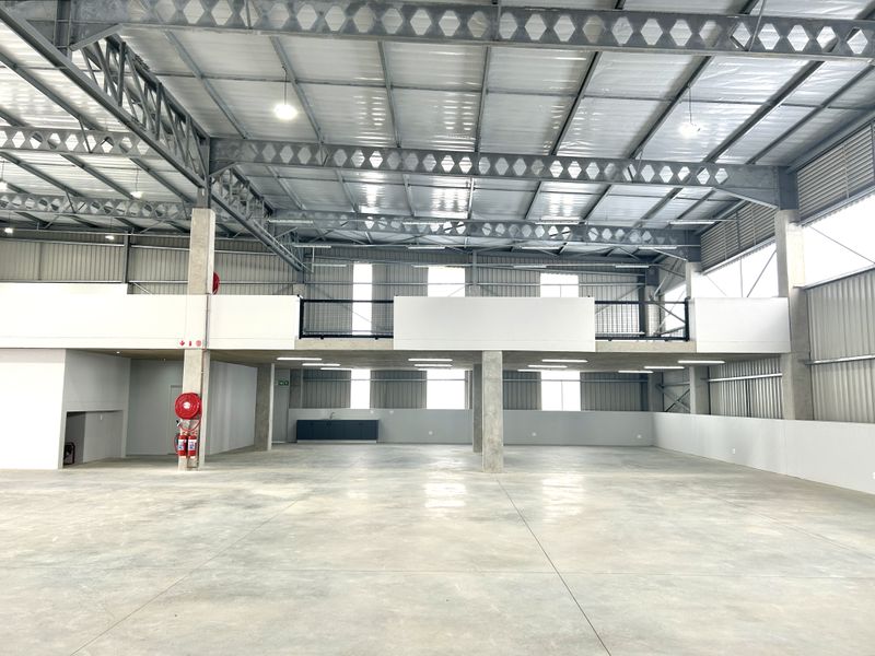 Spacious industrial warehouse featuring high ceilings with exposed steel trusses, polished concrete flooring, and a functional mezzanine level with integrated lighting.
