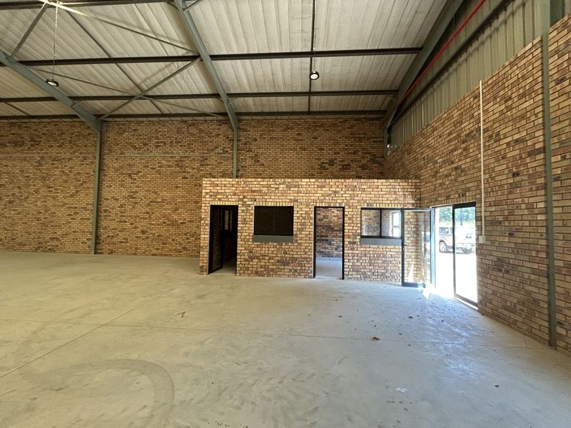 Spacious industrial warehouse unit featuring high exposed steel trusses, durable face brick walls, polished concrete flooring, and a dedicated internal office area.