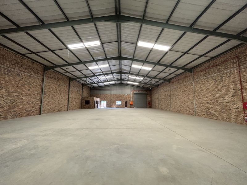 Spacious industrial warehouse featuring exposed brick walls, concrete flooring, high-clearance steel portal frame, and integrated skylights for natural lighting.