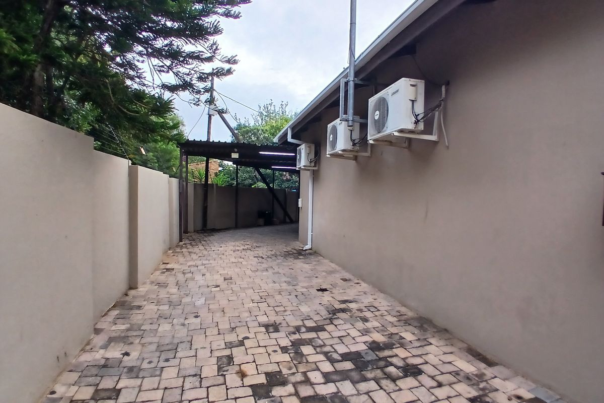 Side exterior area featuring paved driveway, perimeter boundary wall, and wall-mounted air conditioning condenser units.