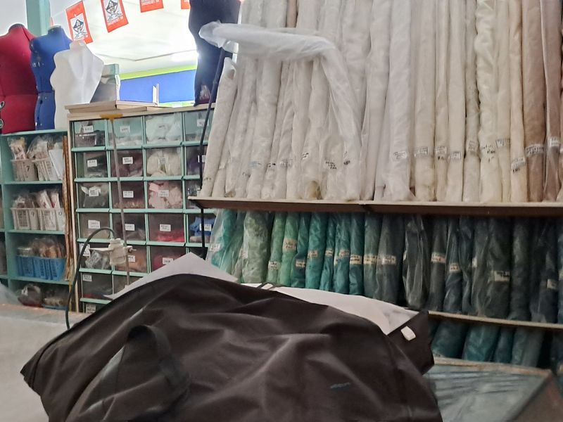 Interior view of a commercial retail space featuring extensive built-in shelving and storage units for fabric and sewing supplies.