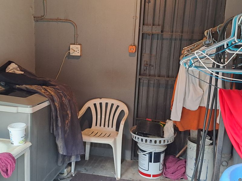 A functional laundry area featuring a utility sink and exposed electrical infrastructure, requiring maintenance and cosmetic updates to improve the space.