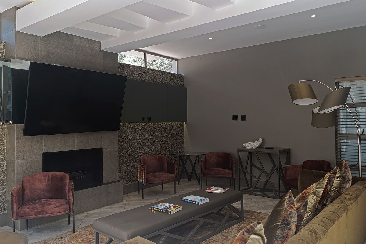 A modern living room featuring a built-in fireplace with stone cladding, coffered ceilings, and recessed lighting, creating a sophisticated and comfortable atmosphere.