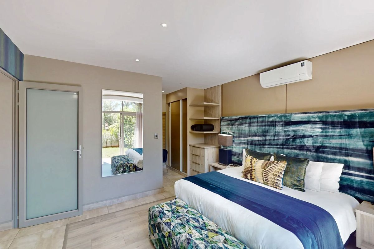 A well-maintained bedroom featuring built-in cupboards, air conditioning, recessed lighting, and tiled flooring with a modern aesthetic.