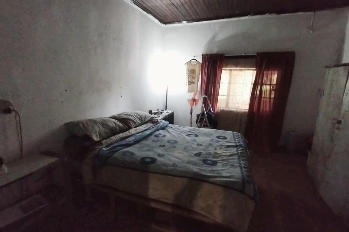 A bedroom featuring a timber ceiling and security bars on the window, requiring cosmetic updates to improve the overall condition and appeal.