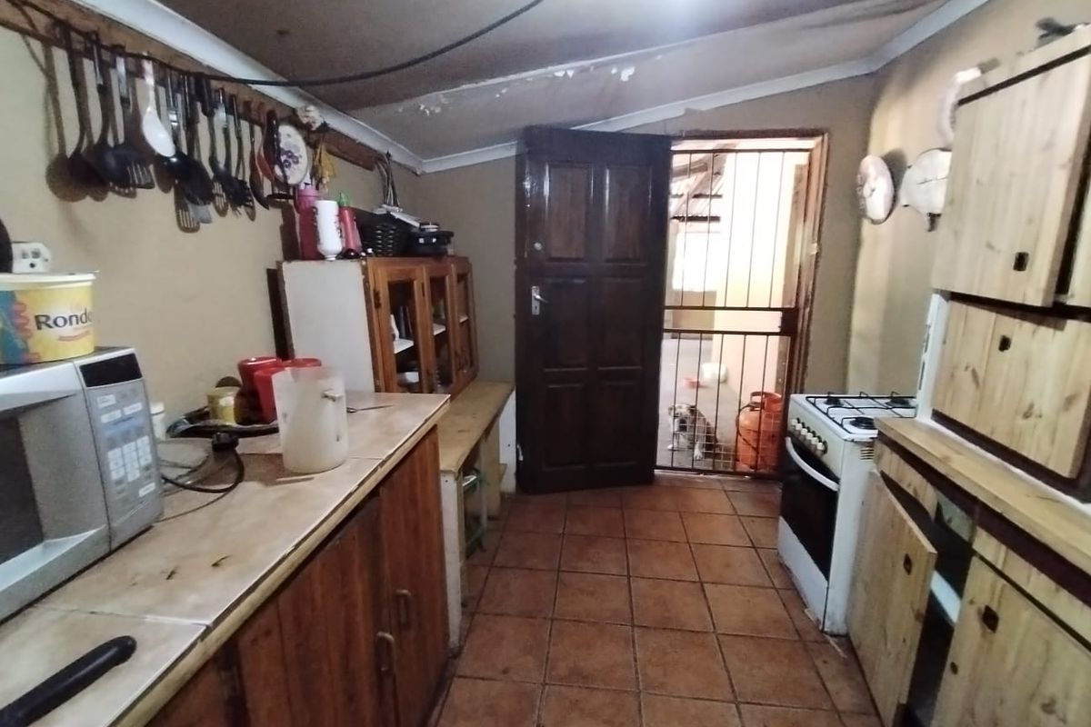 A rustic kitchen featuring wooden cabinetry, tiled flooring, and a gas stove, requiring maintenance and cosmetic updates to improve functionality and aesthetic appeal.