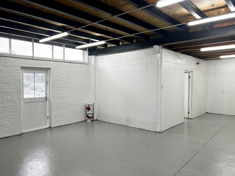 A clean, industrial utility space featuring exposed steel ceiling beams, painted concrete block walls, and durable epoxy-coated flooring with secure access points.