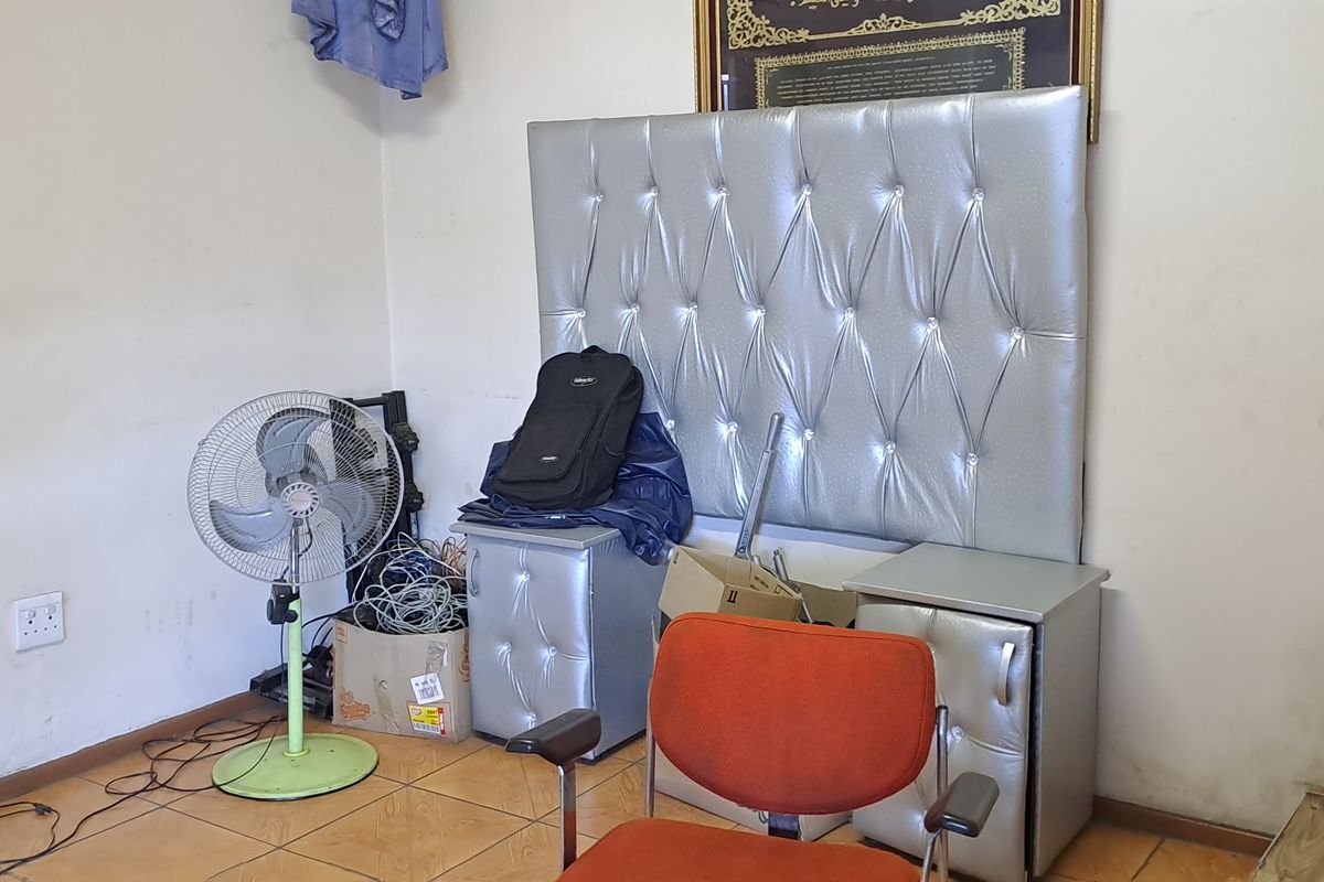 A bedroom space featuring tiled flooring and wall-mounted headboard paneling, currently used for storage.