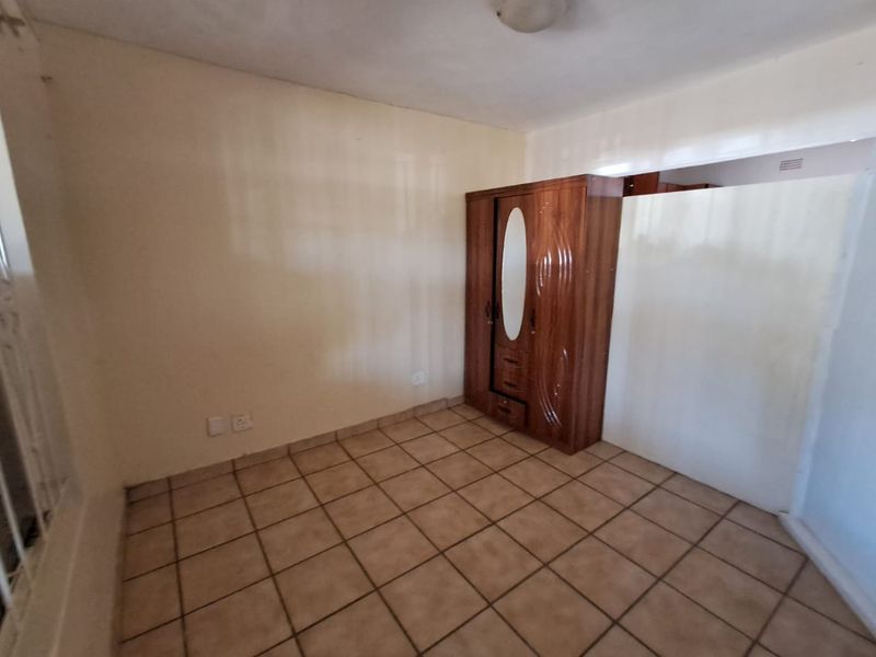 A vacant bedroom featuring ceramic floor tiles and neutral wall finishes, offering a blank canvas for personalization.