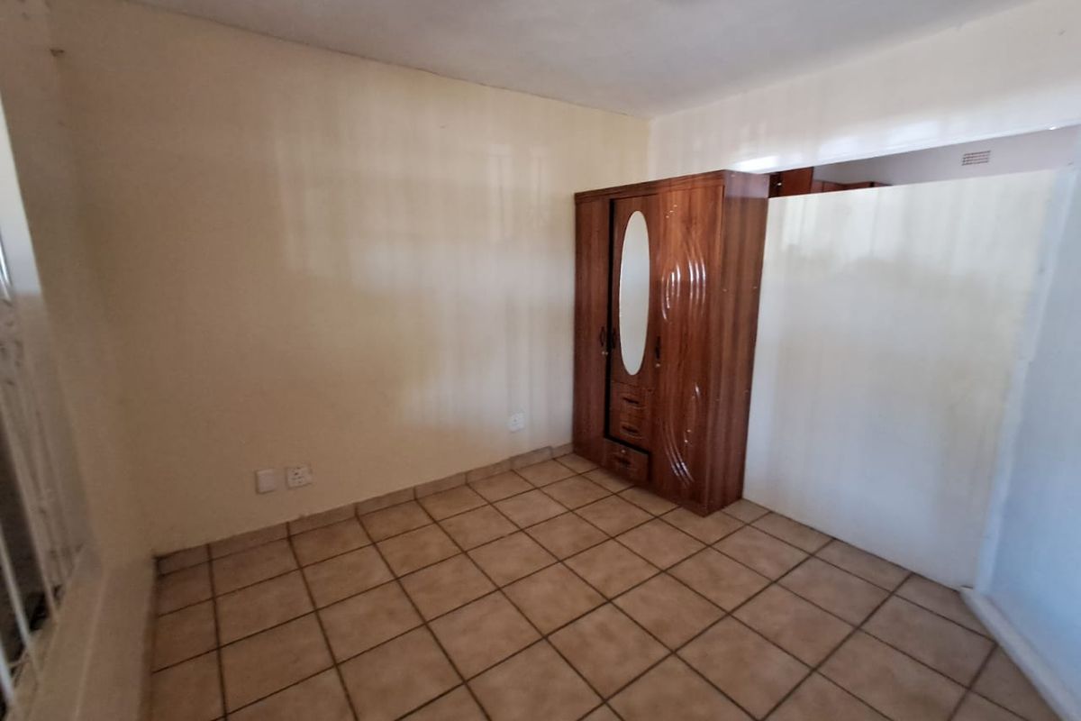 A vacant bedroom featuring ceramic floor tiles and neutral wall finishes, offering a blank canvas for personalization.