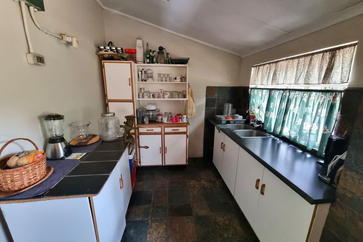 A functional kitchen featuring built-in cabinetry, a double basin sink, and slate tile flooring, offering a practical layout for farm-style living.