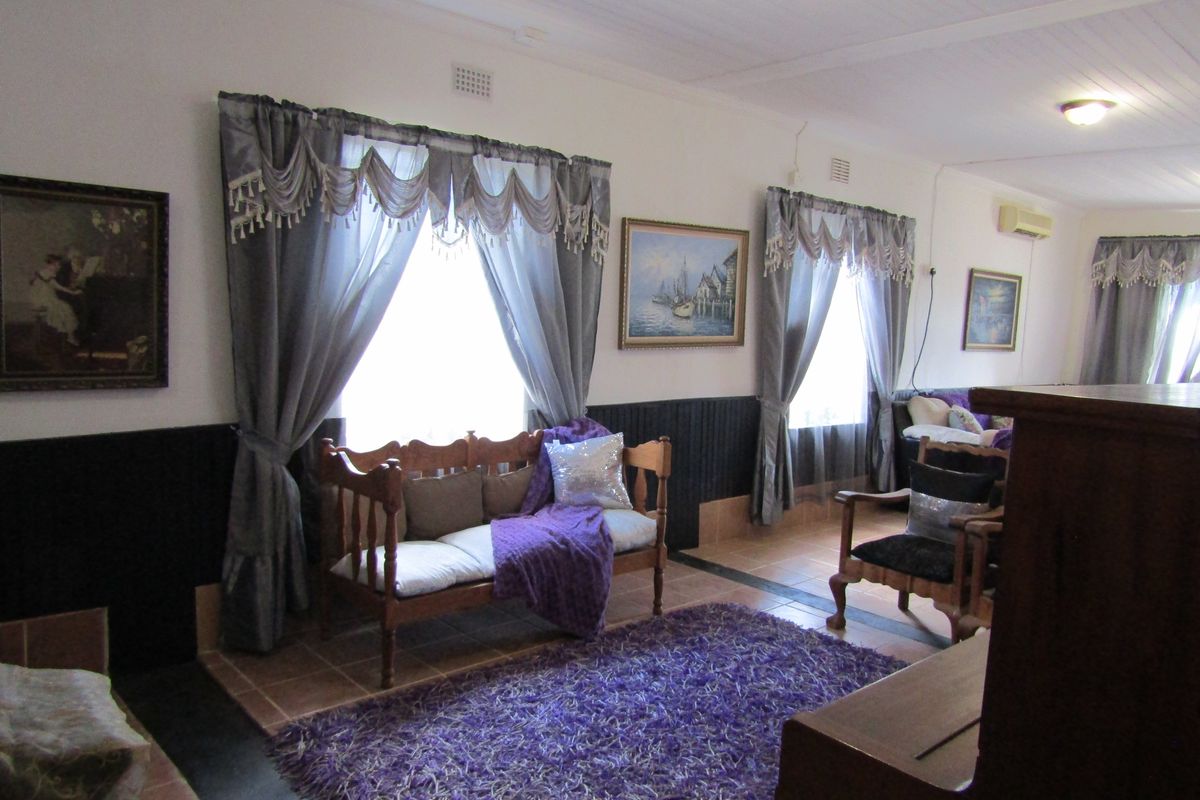 A living room featuring tiled flooring, a tongue and groove ceiling, and a wall-mounted air conditioning unit.
