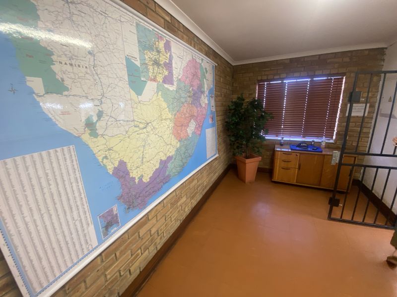 A functional hallway featuring face brick walls, tiled flooring, and a security gate, providing a secure and practical transition space within the retail property.