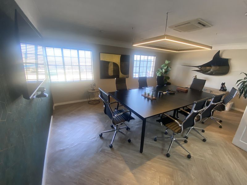 A professional office space featuring herringbone flooring, modern recessed lighting, and ducted air conditioning, creating a clean and functional work environment.