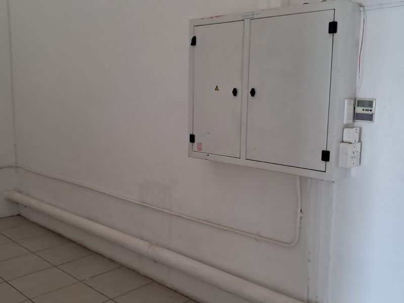 A utility space featuring a wall-mounted electrical distribution board, surface-mounted conduit, and ceramic floor tiles.