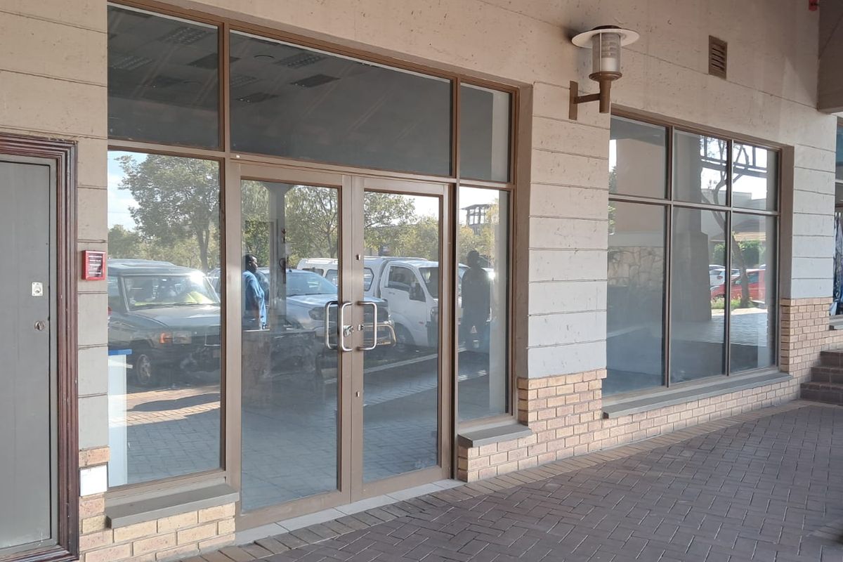 Front exterior view of a retail storefront featuring large glass windows, aluminum framing, and a paved walkway entrance.