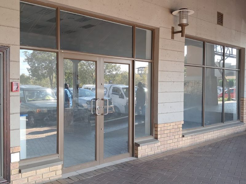 Front exterior view of a retail storefront featuring large glass windows, aluminum framing, and a paved walkway entrance.