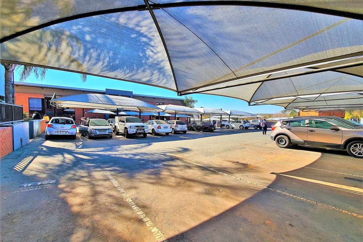 Outdoor parking area featuring multiple shade cloth structures providing covered vehicle bays for the office property.