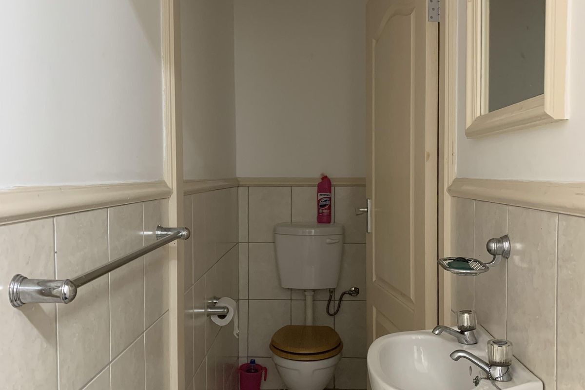 A compact bathroom featuring a wall-mounted basin, a standard toilet, and tiled walls with a dado rail.