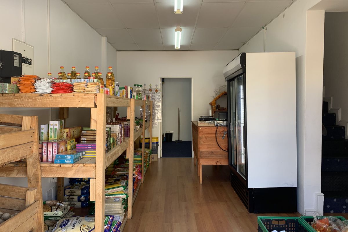 Commercial retail space featuring wood-look flooring, fluorescent ceiling lighting, and a built-in glass-door display refrigerator.