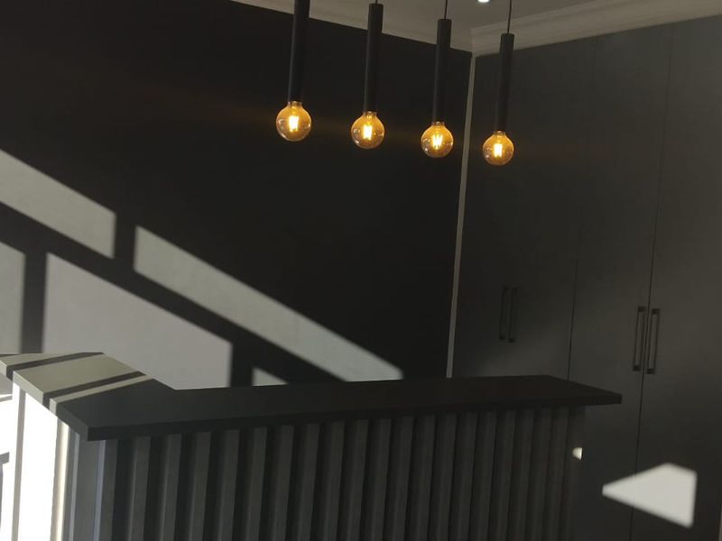 Modern commercial entry area featuring a sleek reception counter, built-in storage cabinetry, and contemporary pendant lighting.