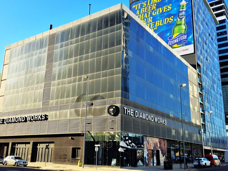 Exterior view of a multi-story commercial office building featuring a glass curtain wall facade and prominent street-level signage in an urban setting.
