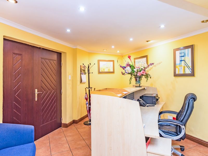A functional reception area featuring tiled flooring, recessed downlighting, and a built-in reception desk, providing a welcoming entry point for the business.