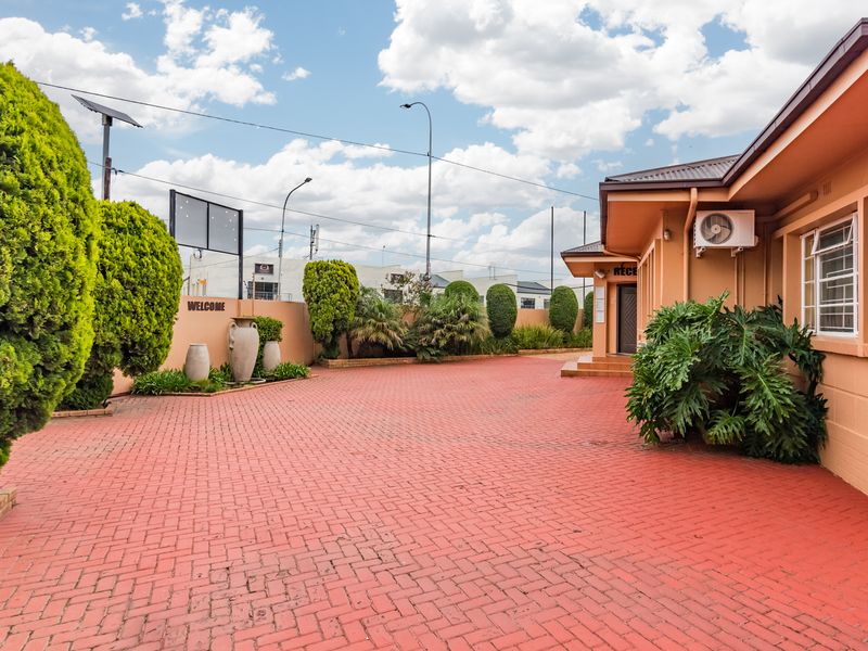 Front exterior view of the business premises featuring a paved driveway, reception entrance, and established garden landscaping.