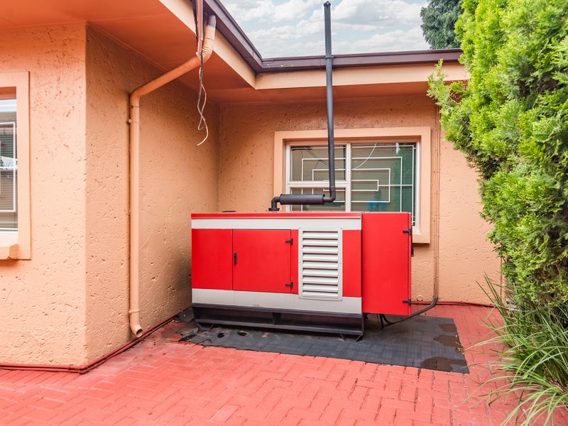 Exterior utility area featuring a backup generator installation with an exhaust flue, set on a paved patio surface.