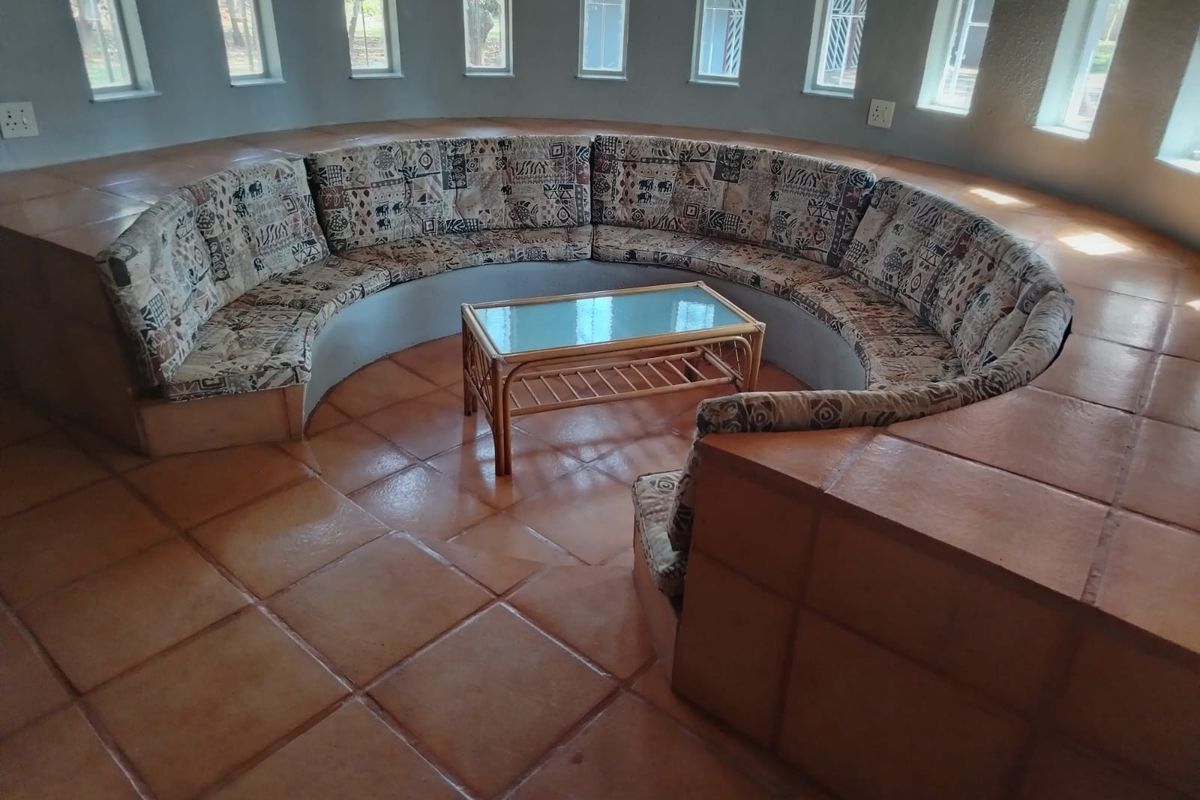 A unique circular living area featuring built-in curved seating, terracotta tiled flooring, and multiple vertical windows providing natural light.