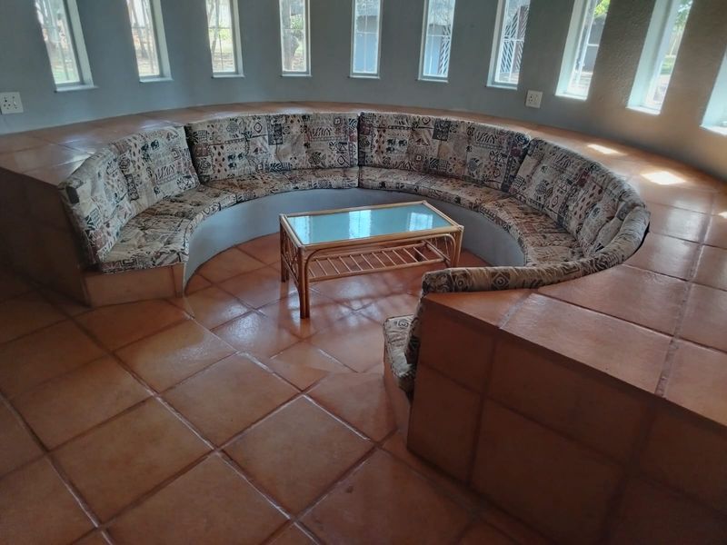 A unique circular living area featuring built-in curved seating, terracotta tiled flooring, and multiple vertical windows providing natural light.
