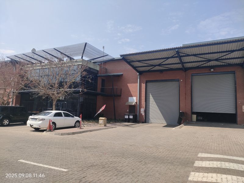 Industrial property exterior featuring brick facade, large roller shutter doors, and a paved driveway area.