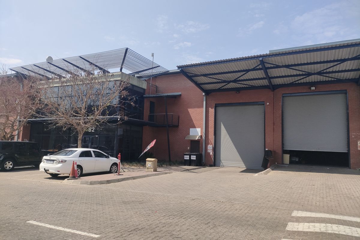 Industrial property exterior featuring brick facade, large roller shutter doors, and a paved driveway area.