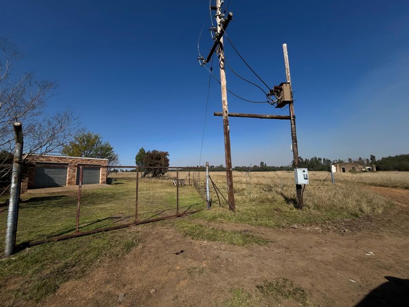 Exterior view of the farm property entrance featuring a double garage, perimeter fencing, and utility infrastructure.