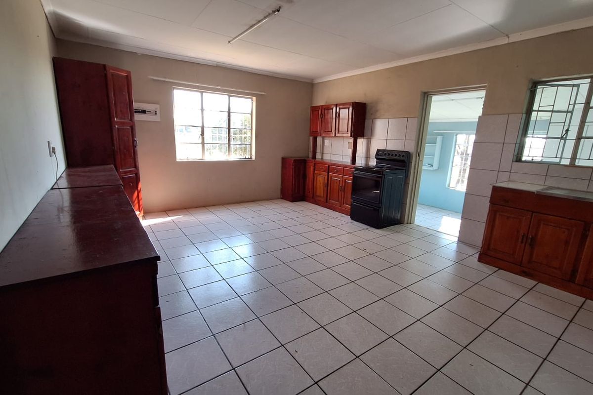Spacious kitchen area featuring tiled flooring, wooden cabinetry, and a freestanding stove, offering a functional layout with potential for modern updates.