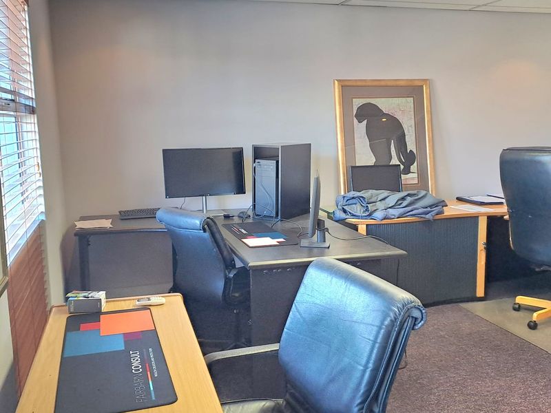 A functional office space featuring a suspended ceiling, recessed lighting, carpeted flooring, and venetian blinds.